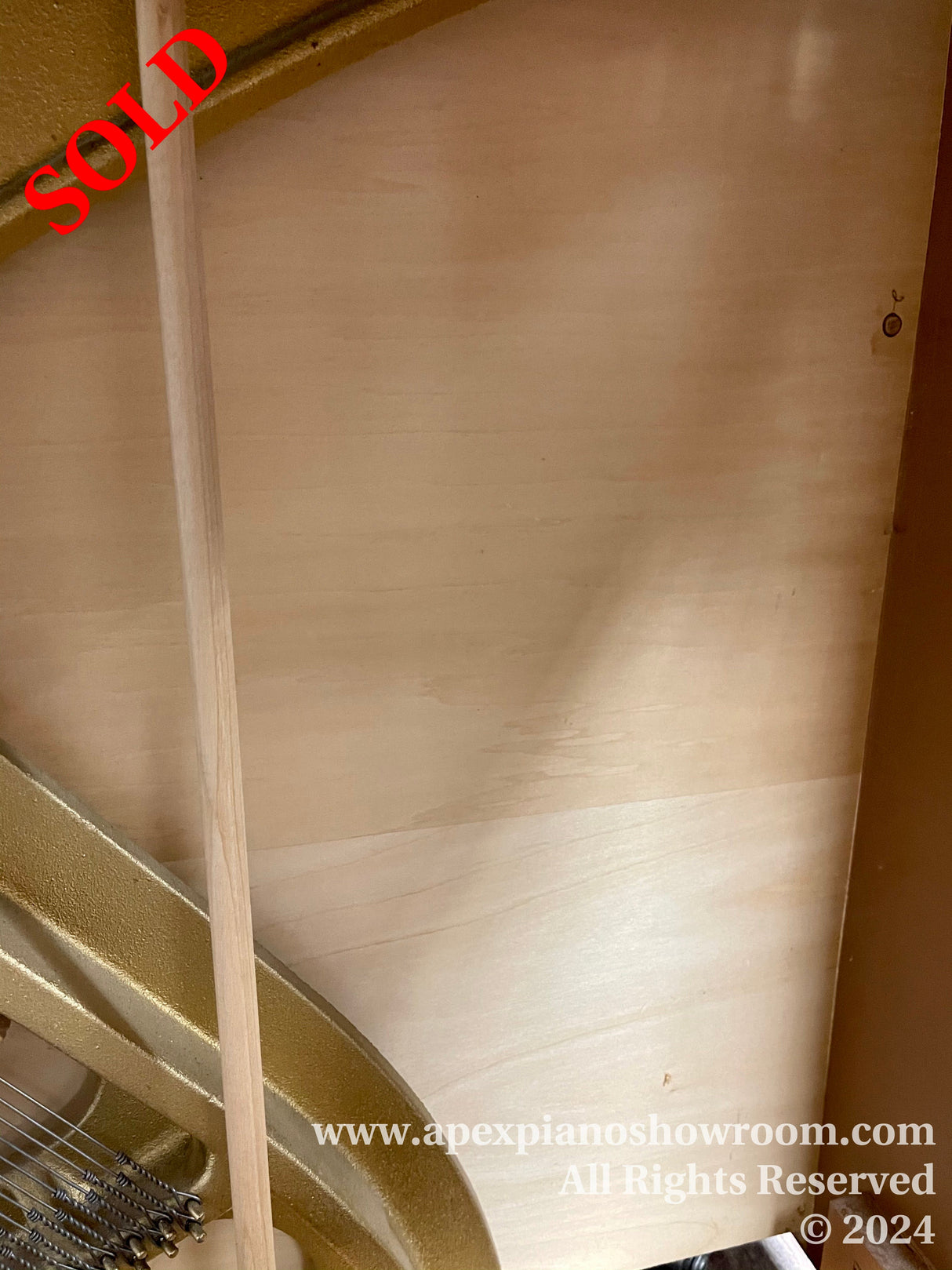 Close-up view of a grand piano's interior showing the soundboard and strings, highlighting the craftsmanship and components used in piano construction.