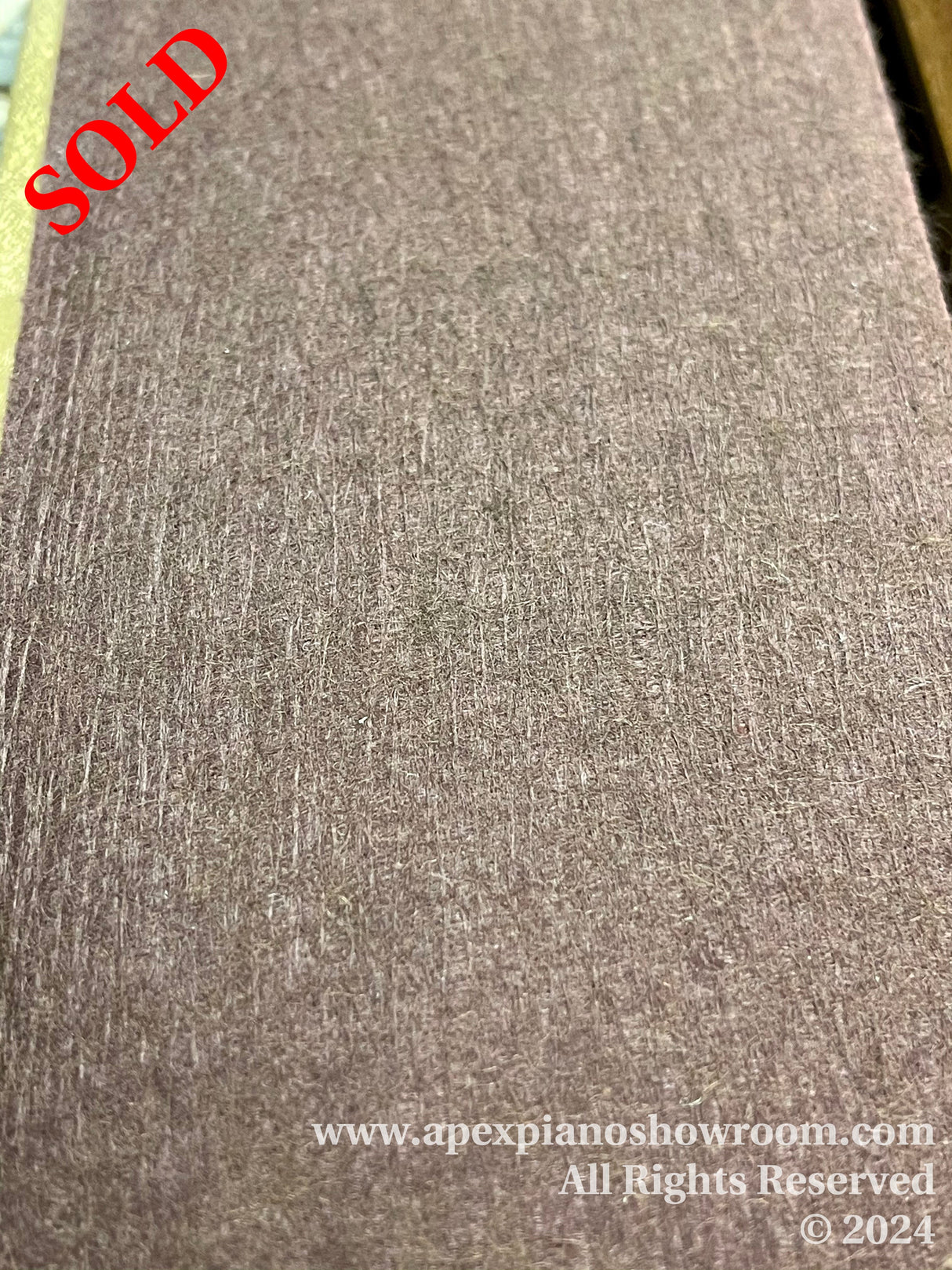 A close-up view of a brown felt piano damper, commonly used under the strings inside a piano to control sound resonance.