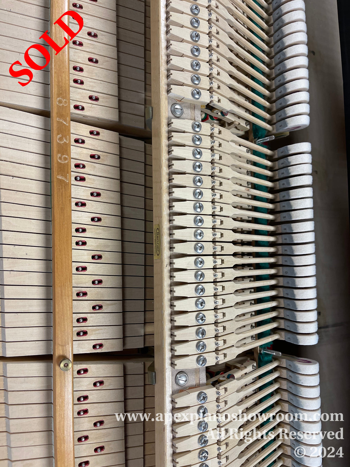 Interior mechanism of a grand piano featuring an array of hammers and dampers, showcasing the intricate design and engineering of piano action components.