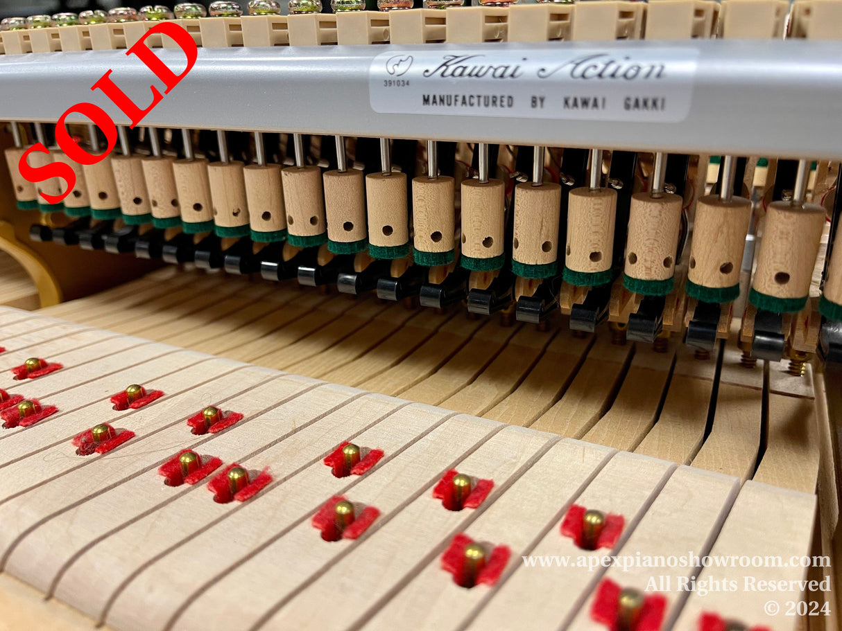 Interior view of a Kawai grand piano action, showing hammers, dampers, and strings, illustrating the complex mechanism responsible for the instrument's touch and tone.