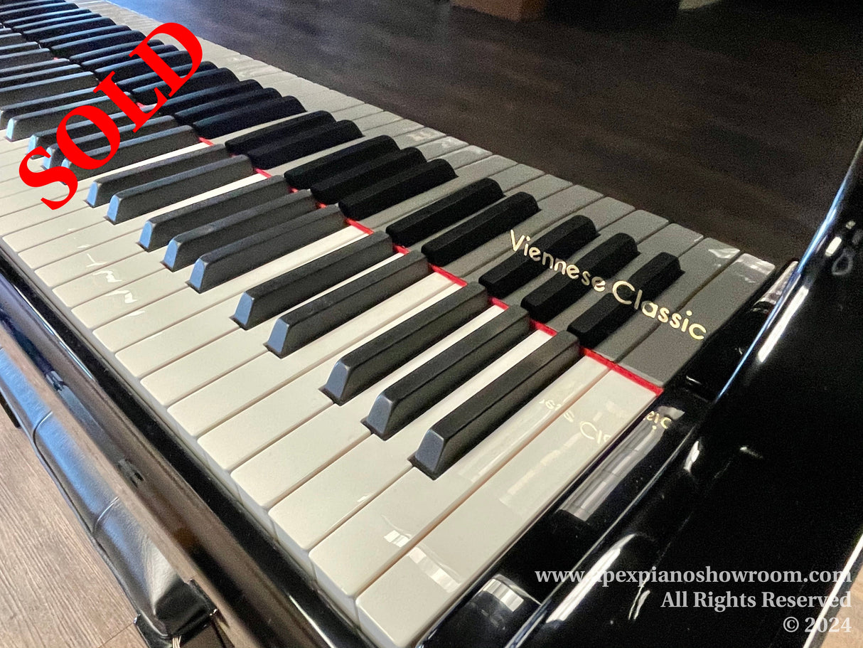 Close-up view of a piano keyboard with black and white keys, the text Viennese Classic labeled on one of the keys, highlighting a specific piano model or style, with a glossy black finish on the pianos surface.