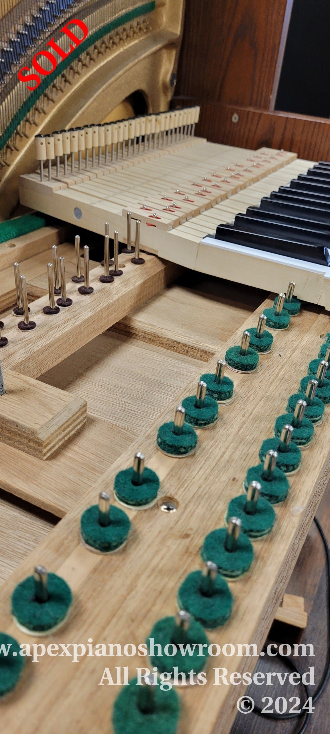 Interior view of a grand piano showing exposed action mechanism, hammers, dampers, and partially removed strings, with a focus on the regulation process of piano maintenance.