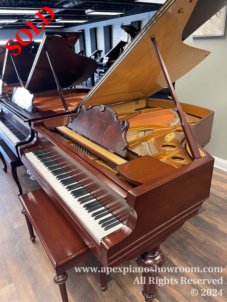 An elegant mahogany grand piano with the lid open displaying its strings and hammers, situated in a showroom with other pianos in the background, reflecting careful craftsmanship and design typical of high-quality musical instruments.