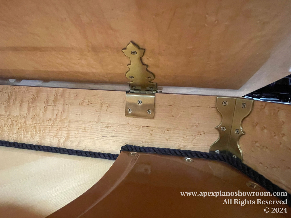 Piano undercarriage with brass hardware and support beams, showcasing the craftsmanship and support structure of a grand piano.