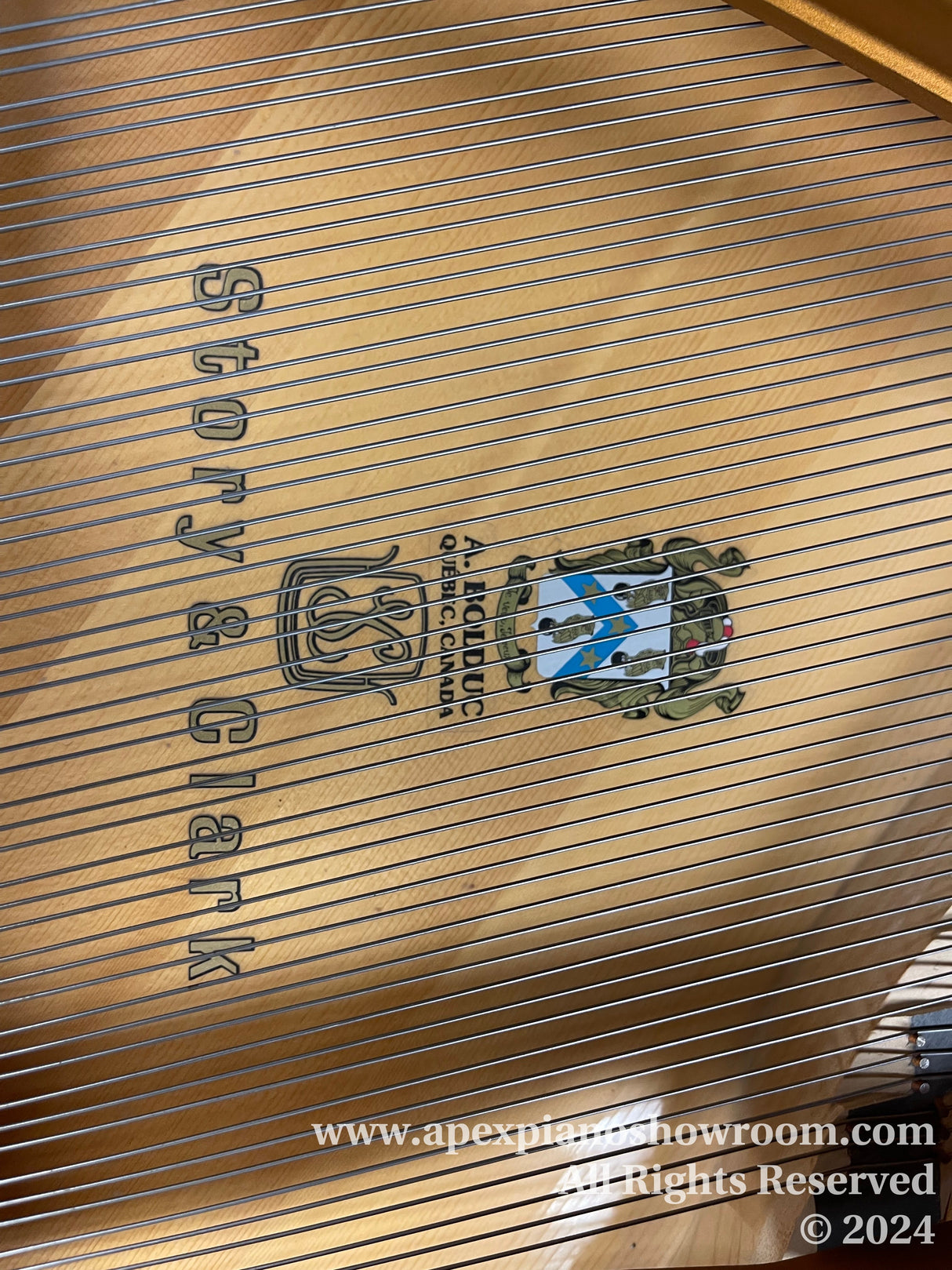 Interior view of a grand piano showing the soundboard, strings, and the cast iron plate with the manufacturers name Story & Clark.