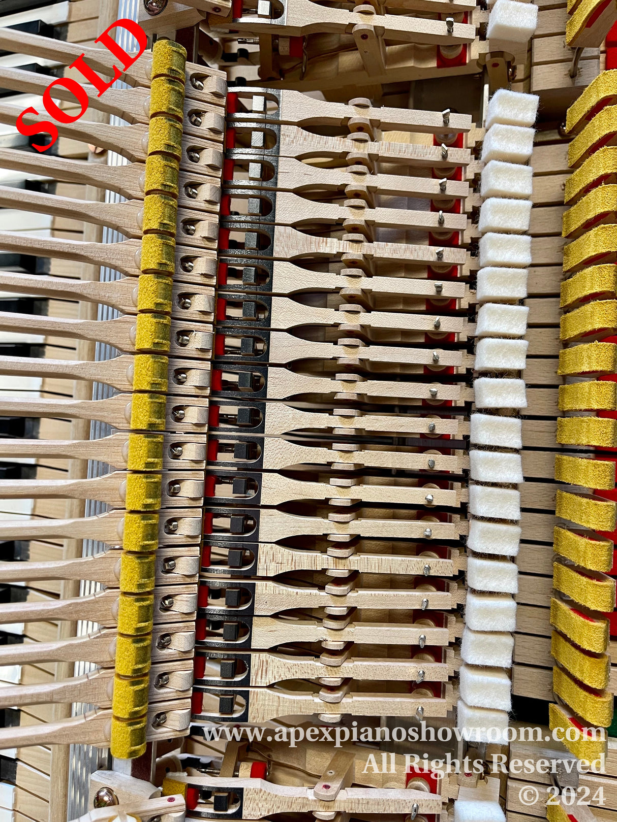 Close-up view of the internal mechanism of a grand piano, showing hammers, dampers, and strings, with details highlighting the precision engineering and craftsmanship of the piano action components.