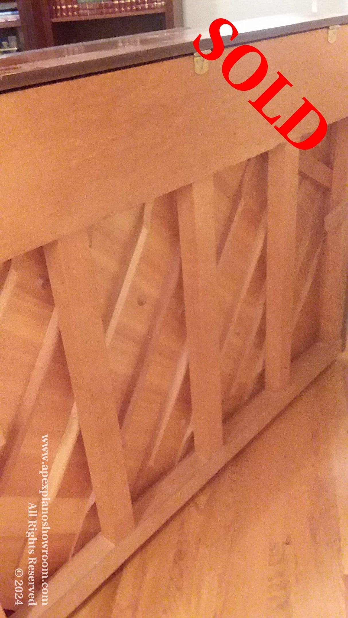 Interior structure of a wooden upright piano showing support beams and soundboard.