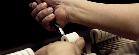 A piano technician carefully regulating the action of a grand piano to ensure proper key movement and response.