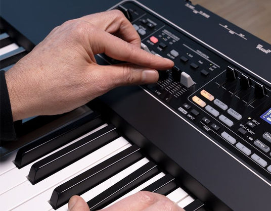 Person's hands playing on a digital piano with focus on the control panel and keys.