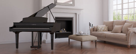 Elegant living room with a black grand piano, beige tufted sofa, ottoman, and a fireplace, with natural light coming through large windows.