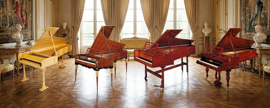 Four different styles of harpsichords on a white background.