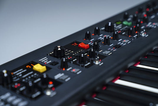 Close-up of a modern synthesizer keyboard with various control knobs and buttons for sound modulation.