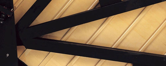 Close-up of the interior strings and soundboard of a grand piano, showcasing the intricate pattern and craftsmanship.
