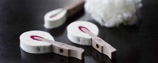 Close-up of piano damper felts and wooden parts on a dark surface, components used in piano action mechanisms.