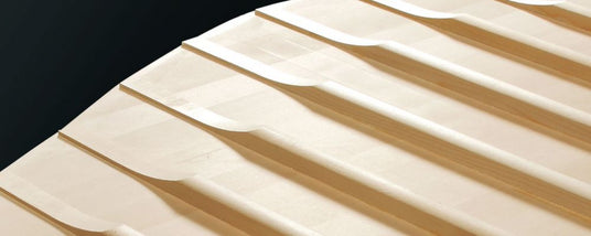 Close-up of piano keys from a grand piano showing the intricate design and craftsmanship of the white keys against a dark background.