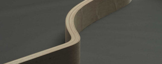 Close-up of a grand piano's curved side, highlighting the craftsmanship and layered wood construction of the piano's casing.