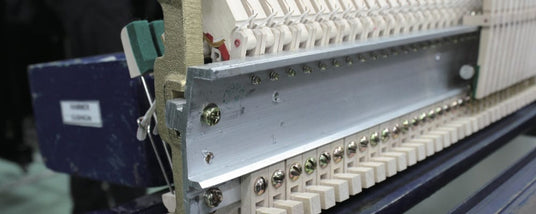 Close-up of piano hammers and dampers assembly in a workshop, showcasing the intricate internal mechanism during tuning or repair.