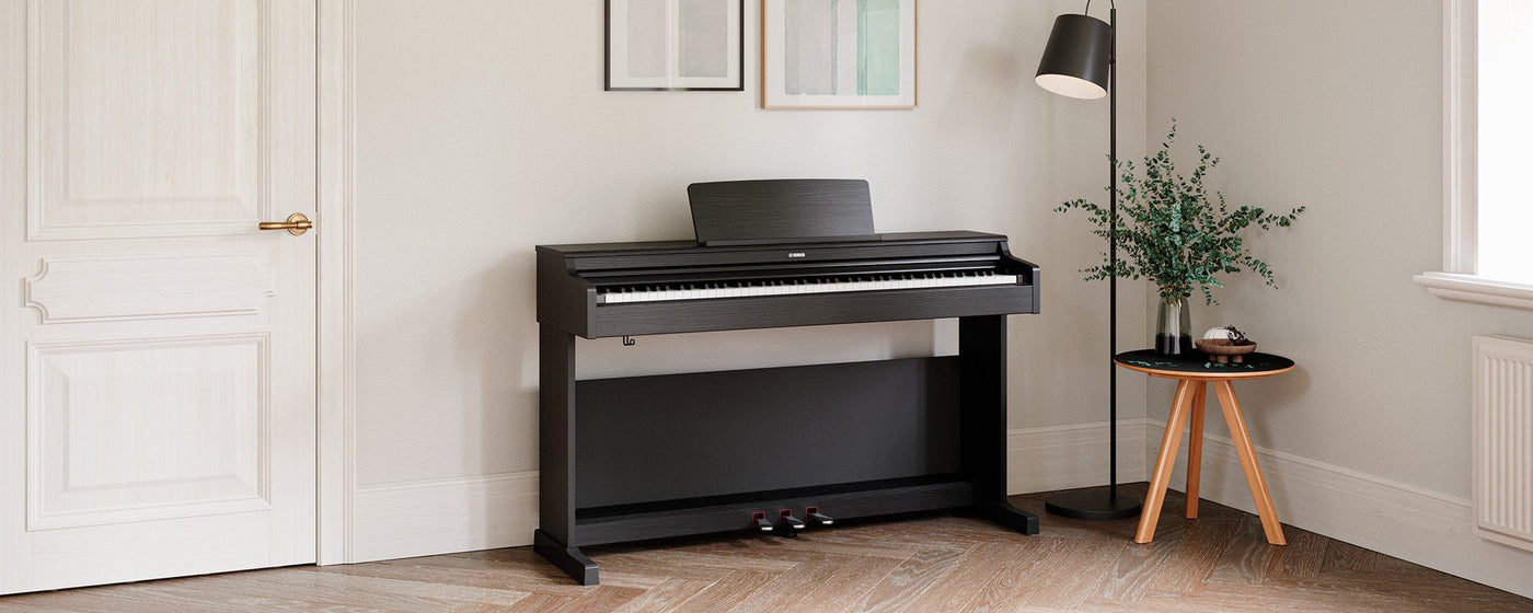 An elegant black digital piano positioned in a well-lit room with minimalist decor, showcasing modern home integration of musical instruments for the contemporary pianist.