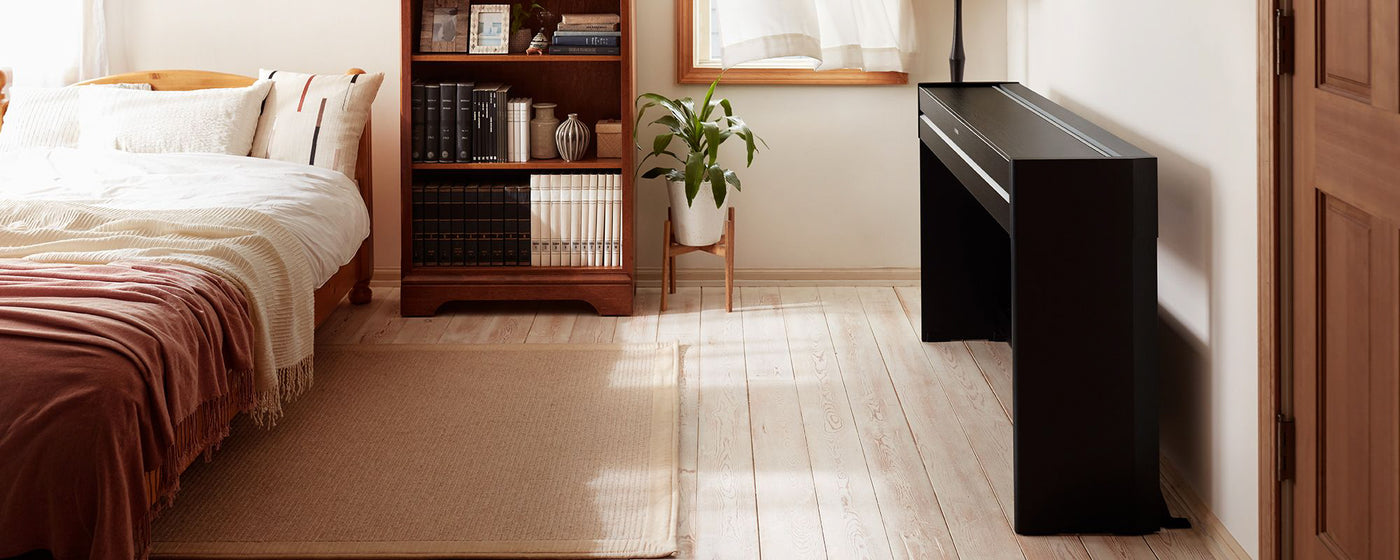 An elegant digital piano in a modern bedroom setting, placed next to a window to create a comfortable space for music practice.