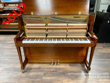 A Baldwin upright piano with an open panel revealing its intricate internal strings and hammers, set in a showroom with wood flooring.