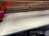 Interior view of a grand piano showing the intricate arrangement of strings and hammers, set against the wooden soundboard, indicative of piano craftsmanship.