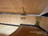 Piano undercarriage with brass hardware and support beams, showcasing the craftsmanship and support structure of a grand piano.