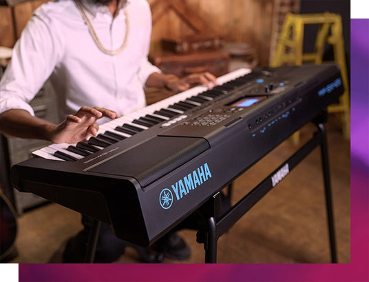 A musician playing a Yamaha digital piano on a stage with warm ambient lighting.