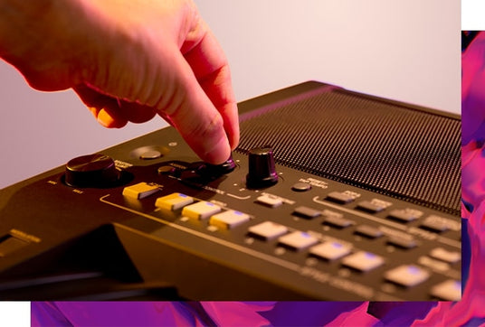 A person's hand adjusting a knob on an electronic keyboard with illuminated keys and control buttons, resembling a modern take on piano technology.