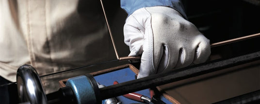 A piano technician's hands tuning a piano, with focus on the tuning lever and piano strings.